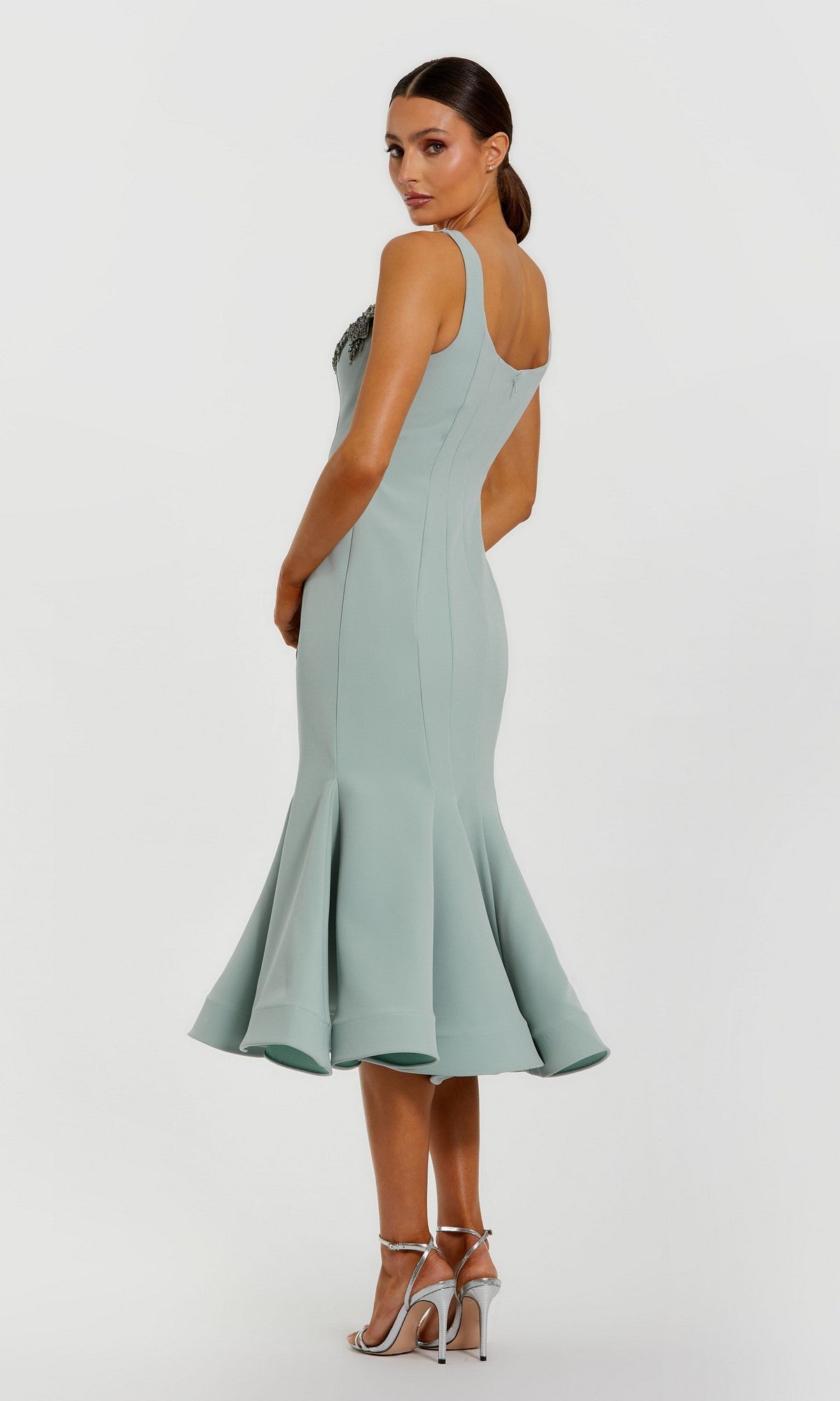 Woman wearing the Midi Wedding Guest Dress: Mac Duggal 11948, a fitted light blue sleeveless midi dress with flared hem, paired with silver high-heeled sandals, standing against a plain white background.